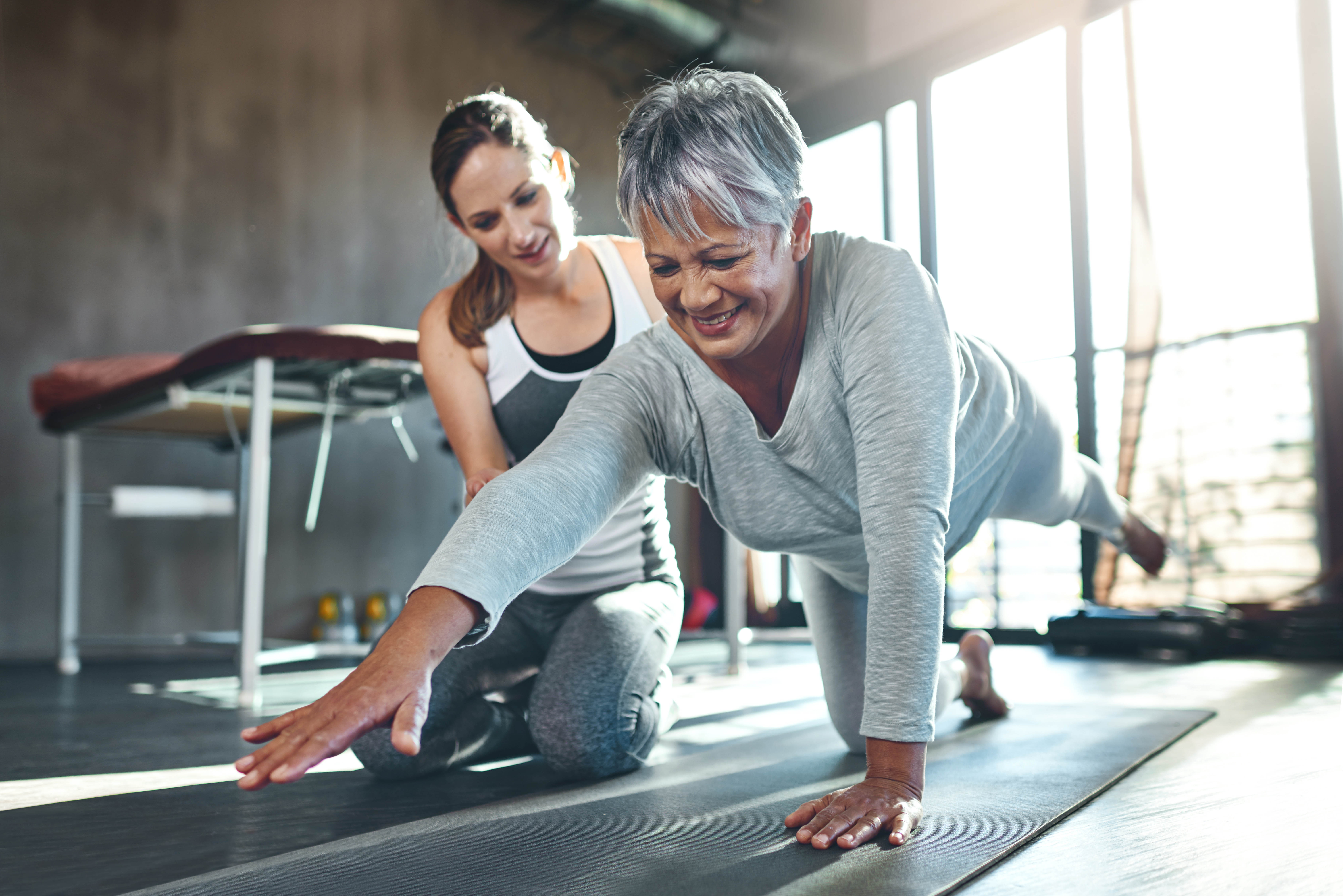 Older woman doing personal training with a female trainer in a gym 